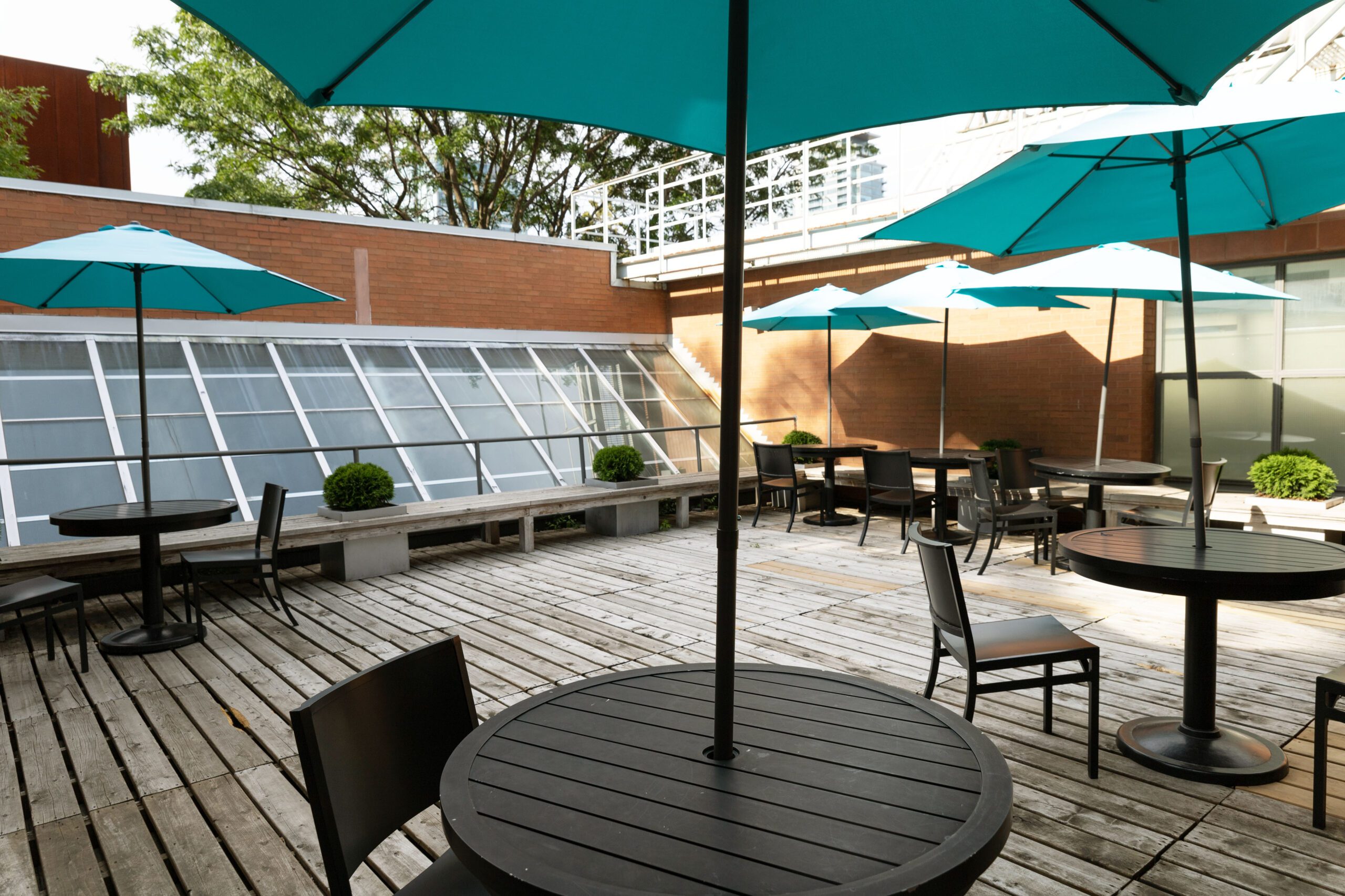 round patio tables with umbrellas and chairs furnish the innis rooftop patio