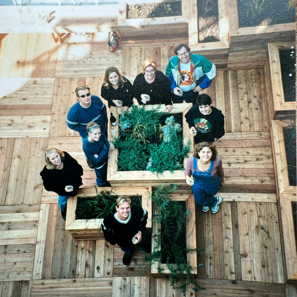 bird's eye photo of a group of students leaning around a wooden garden planter box