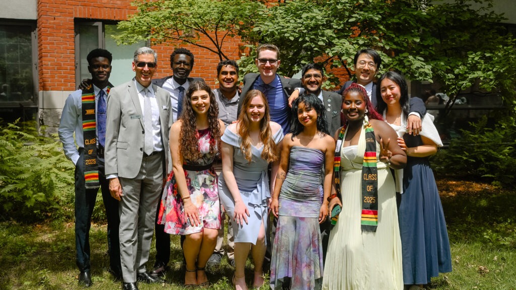 a group of students in semi-formalware poses with the Innis principal in the residence quad