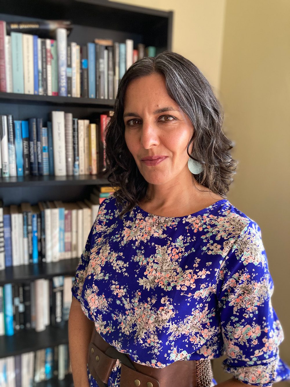 headshot of charlotte gill standing in front of a bookcase