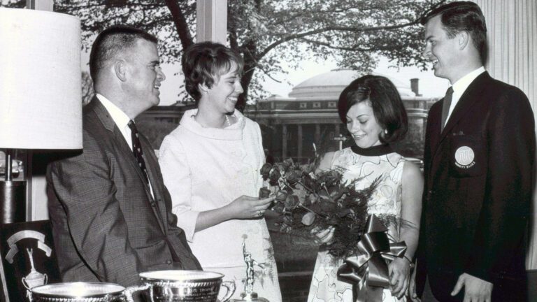 a black and white photo of two students receiving awards from two staff members