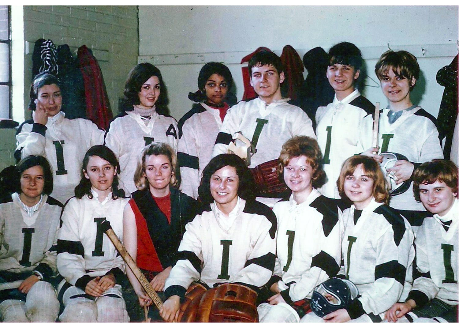 Women's Hockey Team posing for a photo. They are dressed in their uniforms and holding hockey equipment.